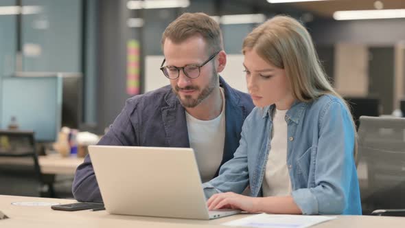 Male Colleague Harassing Female Colleague While Working on Laptop in Office