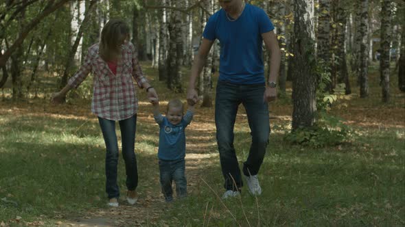 Happy Young Family Is Having Fun in the Autumn Park Outdoors on a Sunny Day. Mother, Father and