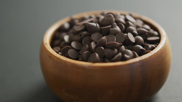 Video of close up of wooden bowl of chocolate chip over grey background