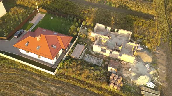 Top Down Aerial View of Two Private Houses One Under Construction with Wooden Roofing Frame and