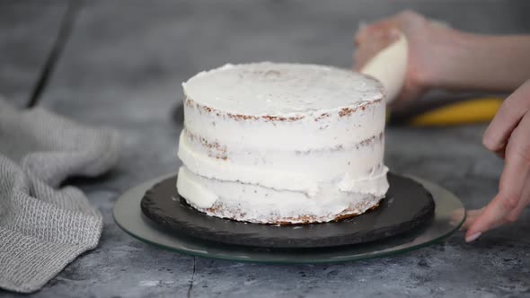 Confectioner Rotates the Cake on a Stand and Decorates with Cream From the Pastry Bag