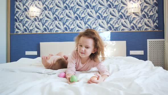 Two Little Sisters are Lying on a Spacious Bright Bed