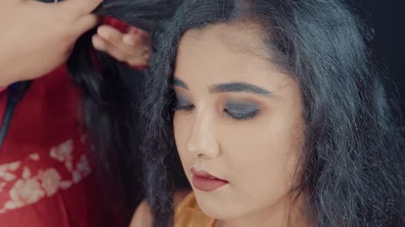 Close up of beautiful and young woman in cosmetics studio making a hairstyle