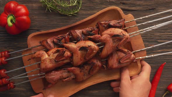 Top View of Fried Quails on the Skewers on the Wooden Plate Placed on the Table