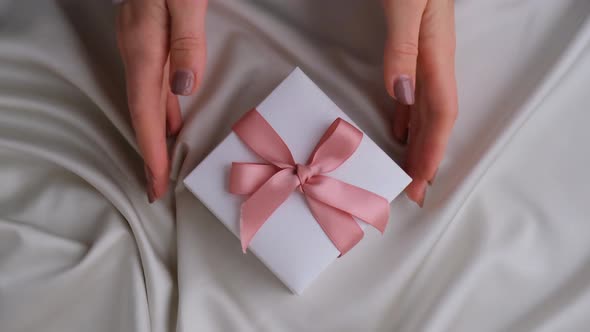 Female Hands Giving and Taking White Gift Box with Pink Ribbon