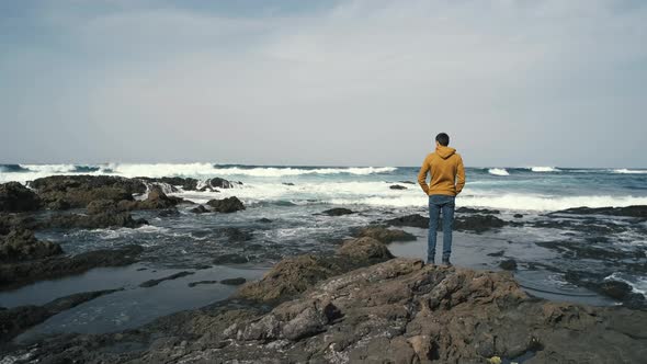 Tourist Man in Yellow Sweatshirt Walks on Volcanic Beach in North of Canary Island Tenerife