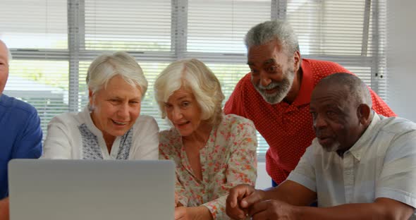 Front view of active mixed-race senior people using laptop at nursing home 4k