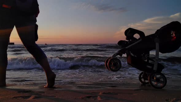 People Walking Along The Beach At Sunset