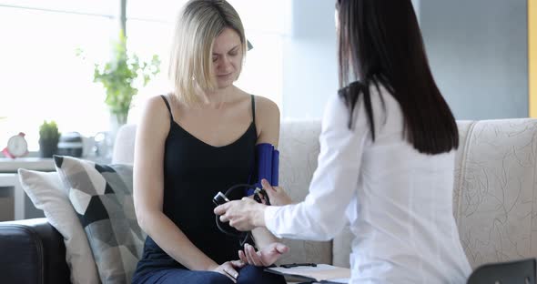 The Doctor on the Couch Measures the Woman's Blood Pressure