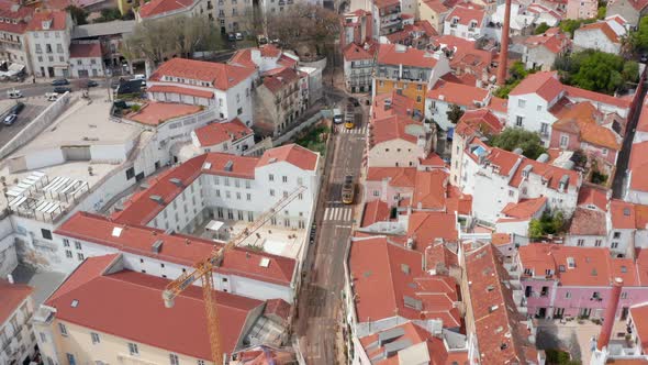 Aerial View of Iconic Trams Driving on the City Streets of Lisbon Between Colourful Traditional