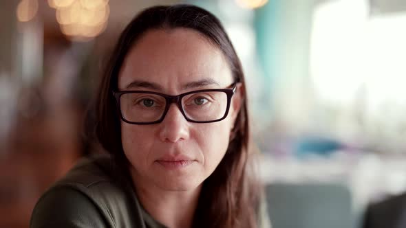Intelligent Pretty Woman with Glasses is Looking at Camera Playfully Portrait in Restaurant