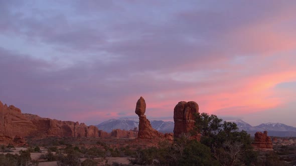 Revealing Balanced Rock during colorful sunset from behind bush