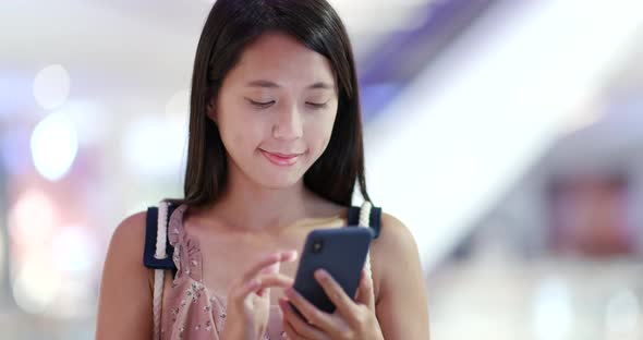 Woman use of mobile phone with the shopping mall background