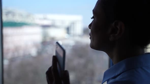 Silhouette of Woman Calling on Cellphone By Window