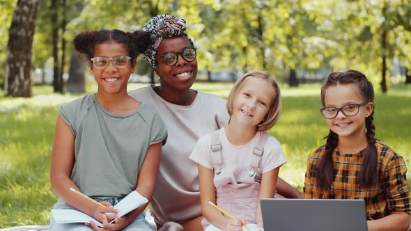 Positive Diverse Girls and Female Teacher Smiling at Camera Outdoors in Park