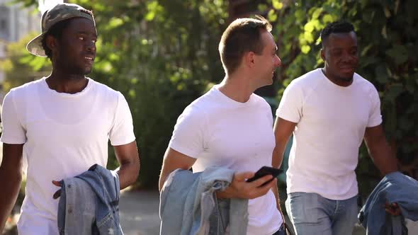 Three Multiracial Friends Walk the City in White T-shirts