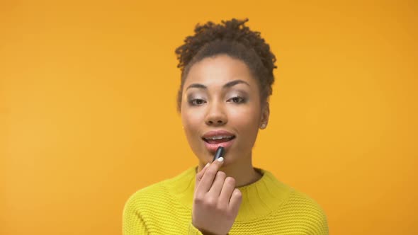 Black Woman Putting Lipstick and Sending Air Kiss to Camera, Enjoying Outlook