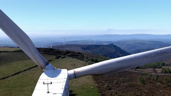 flying above the wind turbine in the idyllic mountainous setting with cattle grazing, sunny clear bl