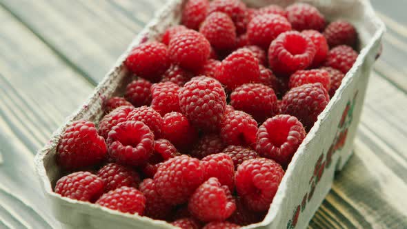 Container with Ripe Raspberry on Wooden Desk 