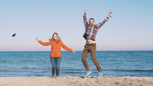 Happy Young Couple Jumping on the Sea Beach Slow Motion