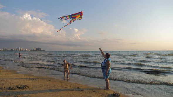 Grandmother and Granddaughter Play with Kite on the Seashore.