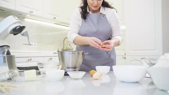 A Woman Breaks an Egg and Separates Yolks From Proteins