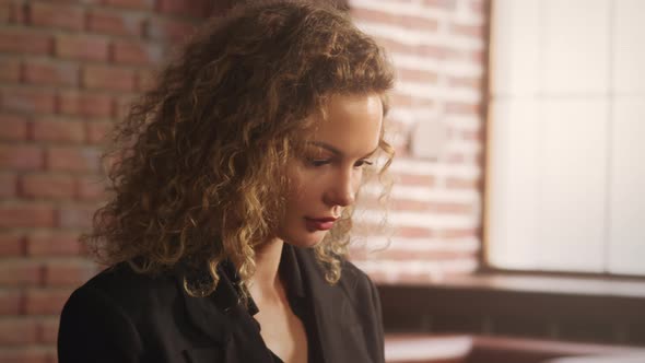 Close Up of a Young Stylish Businesswoman Working on a Laptop in a Loft Apartment with Red Brick