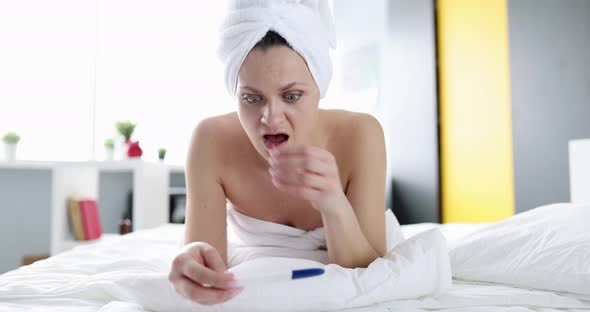 Upset Woman Holding Pregnancy Test and Crying on Bed