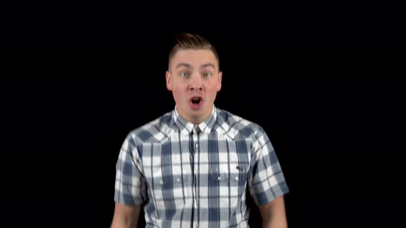 The Young Man Shows Emotions of Surprise on His Face. Surprised Man in a Shirt on a Black Background