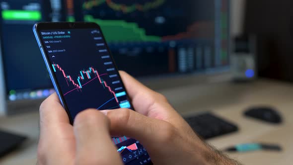 Trader checks Bitcoin market price graph on smart phone device, close up