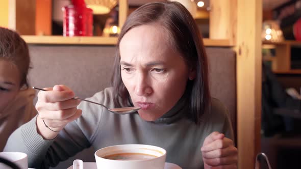 A Woman in a Cafe Eats Asian Tom Yum Soup