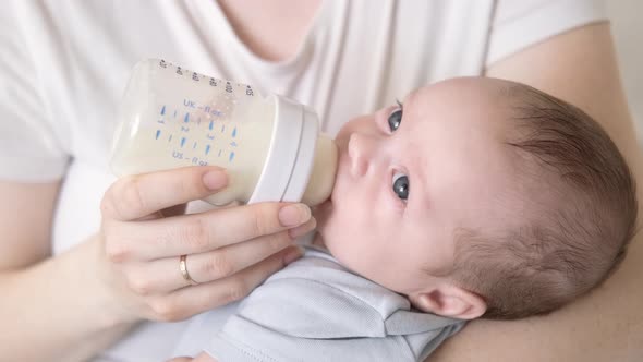 Loving Mother Feeding Her Little Boy Child with Milk Baby Bottle at Home Portrait Infant Baby Eating