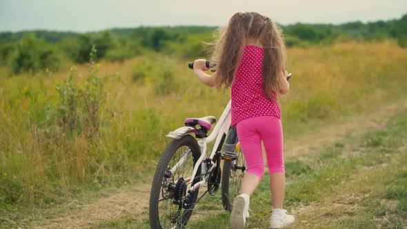 Little Girl with a Bicycle in Nature