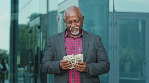 Mature Man with Pile of Dollars Counting Paper Banknotes