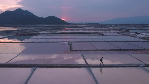 Silhouette of explorer walking through vast endless salt fields during golden hour in Phan Rang, Vie