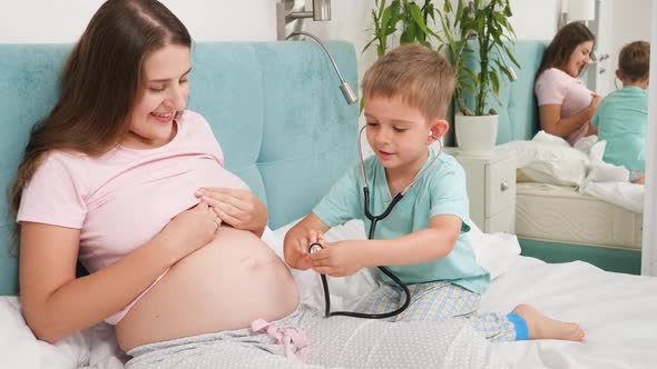 Little Boy Listening To Mothers Pregnant Big Belly with Stethoscope