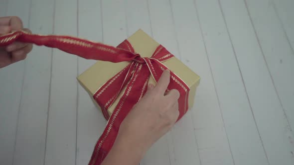 Slow motion hand girl untight bow to open the gift box.