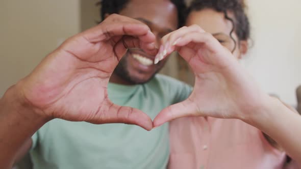 Happy biracial couple gesturing heart sign with hands