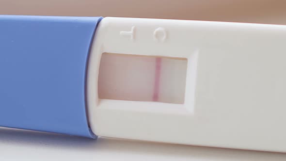 The Camera Slowly Moves Along the Blue and White Pregnancy Test and Two Stripes Appear on It