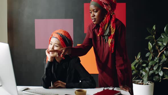 Female Muslim Coworkers Talking by Desk