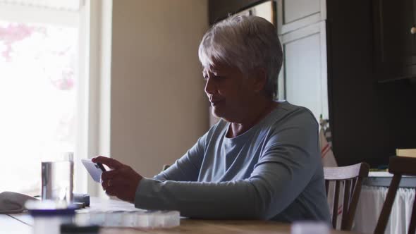 Senior mixed race woman having video chat on smartphone in kitchen