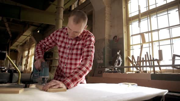 Concentrated Caucasian Male Carpenter Using Jigsaw Tool to Cut Wooden Workpiece in Joinery