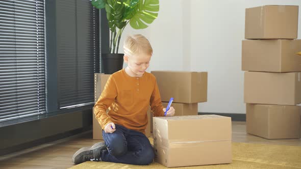 Boy Labelling Boxes Getting Ready For Moving Day Into New Home