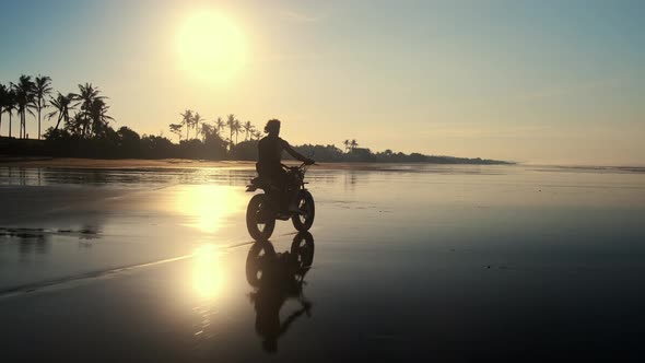 Biker Riding Motorcycle at Dusk Along the Ocean