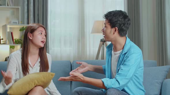 Angry Young Asian Couple Sit On Couch In Living Room Having Family Fight Or Quarrel Suffer