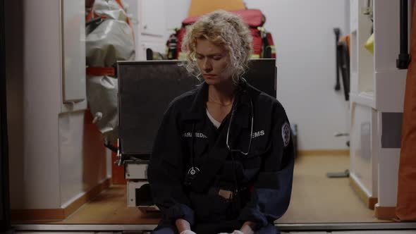 Female Paramedic Sitting in Ambulance and Feeling Sad