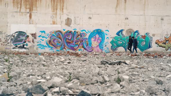 New generation of young people walking in front of graffiti.