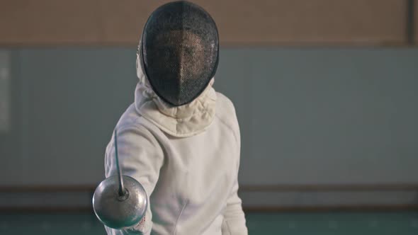 A Young Woman Fencer in Protective Suit and Helmet Making Lunges To the Camera