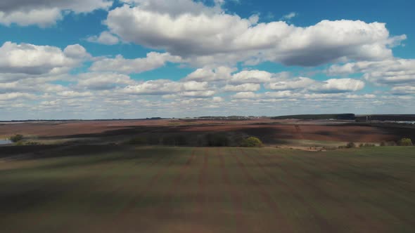 The Tractor Plows the Ground on the Field at the Beginning of the Planting Season. The Camera Is