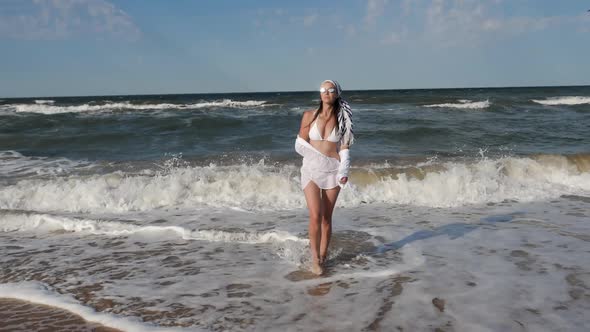 Brunette Woman in a White Swimsuit Stand Along a Sandy Beach